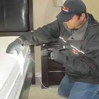 Bed bug inspection technician checking a mattress and bed frame for signs of infestation in Chula Vista, CA