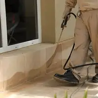 General pest control technician spraying exterior perimeter around a home in Chula Vista, CA