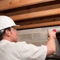 Termite inspection technician checking a basement wall and framing for termite activity in Chula Vista, CA