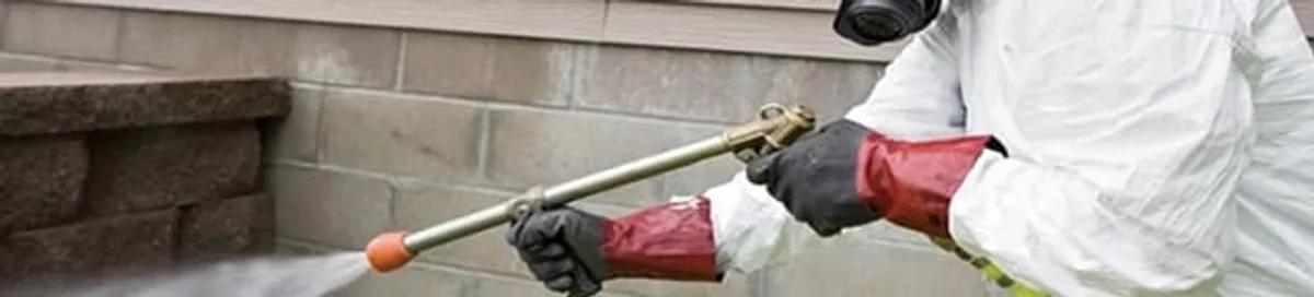 Pest control technician applying exterior insect treatment along a home foundation in Chula Vista, CA